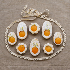 Cookies in the shape of white eggs with apricot yolk with pistachios as homemade decoration