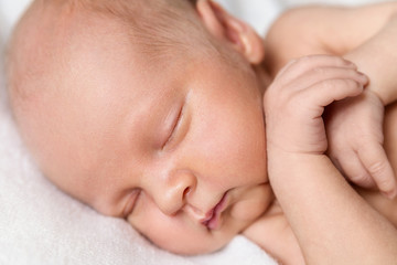 Newborn baby boy on a white background. Baby is sleeping. Boy sleeping with arms under his head