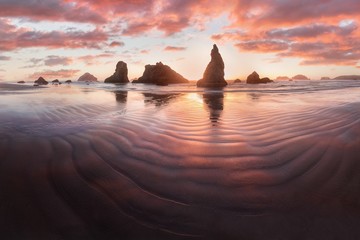 Tropical colourful sunset on the beach. Panorama view of sea with protruding stones and sand...