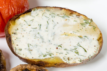 Baked potato with white sauce closeup.