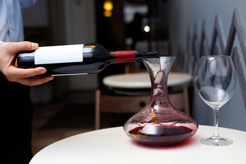 sommelier is pouring wine into a decanter