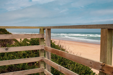 Wooden platform overlooking a wild south african beach; ocean waves and golden sand