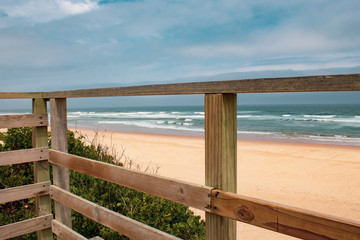 Fototapeta na wymiar Wooden platform overlooking a wild south african beach; ocean waves and golden sand