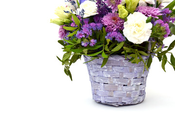 Isolated bouquet of spring flowers in decorative wicker wooden basket of lilac and purple flowers on a white background