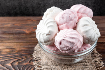White and pink marshmallow on dark wooden background.