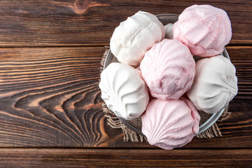 White and pink marshmallow on dark wooden background.