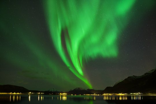 Universal photo with Aurora borealis dancing on a mountains. Beautiful northern lights above the mountains and the harbor and the coast Beautiful northern lights background concept. Night photo Tromso