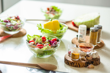 Kitchen table with salads and spices in bottles