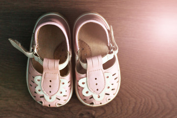 Pink children's handmade shoes, top view, wooden background