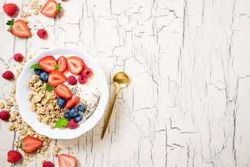 Granola for breakfast with berries and yoghurt. Cereal oatmeal or  muesli with strawberries, blueberries and raspberries. Concept dieting, healthy food and eating. Top view, copy space