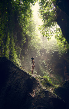 Waterfall Tukad Cepung. Waterfall in Bali. The gorge. A girl in a bathing suit at the waterfall Travel.
