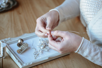 Fototapeta premium Closeup macro photo of details, workplace of decorator and creator of wedding imitation jewelry. Woman's hands in a process of creation