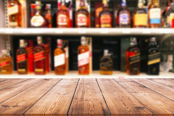 Wood table top and wine Liquor bottle on shelf blurred background