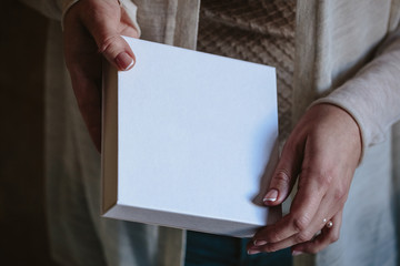 Woman's hands hold a white blank box with wedding handmade jewelry inside