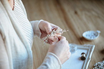 Closeup macro photo of details, workplace of decorator and creator of wedding imitation jewelry. Woman's hands in a process of creation