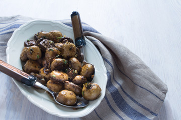 Karamelisierte Champignons mit Aceto, Knoblauch, Kräutern auf einer Servierplatte