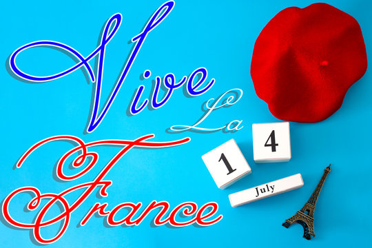 Happy Bastille day, long live France and French national day concept with a flat lay image of red beret, a block calendar set on July 14, a miniature of the Eiffel Tower and the text Viva La France