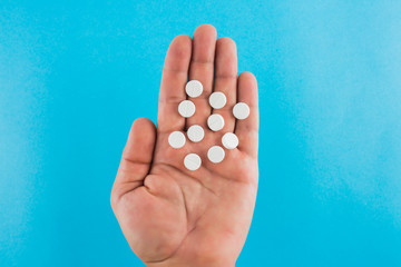 hand holding two pills over blue background