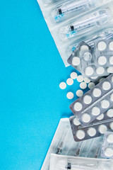 packs of white pills and syringes on a blue background