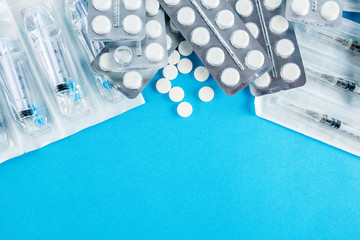 packs of white pills and syringes on a blue background