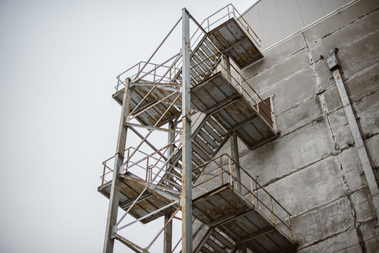 Fire Escape metal stairs on concrete classic building wall. Old urban building with fire escape.