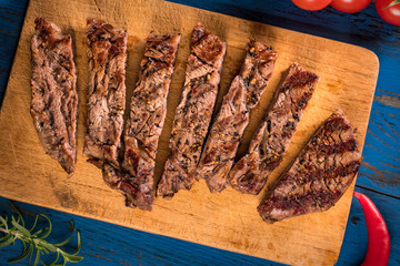 Grilled steak with spices on a dark blue wooden table