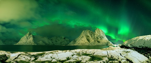 Aurora borealis dancing on mountain in fishing village at Reine and Sakrisoy, Lofoten, Norway Visiting the Lofoten Islands during winter time is a dream for all landscape photographers Christmas time - obrazy, fototapety, plakaty