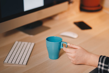 Coffee mug on a wooden table, in front of the working computer. Home office concept, personal working space.