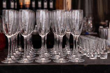 Rows of clear clean champagne glasses and vodka glasses at the bar in the restaurant