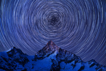 Incredible night view in Swiss Alps. Star trails moving in blue sky. Zermatt resort location,...