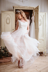 Fototapeta premium Beautiful bride blonde woman sitting near vintage wardrobe full of wedding dresses. fashion beauty portrait 
