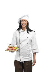 Young confectioner in uniform holding tray with sweets.