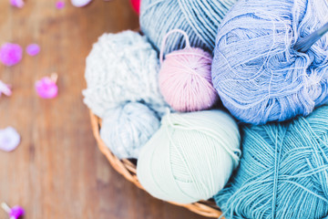 Fototapeta na wymiar Womens hobby. Skeins of yarn and knitting needles in the basket on wooden background. 