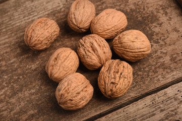 Walnut kernels and whole walnuts on rustic old oak table.