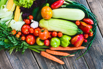 The harvest of vegetables. Vegetables (carrots, corn, cucumbers, tomatoes, onions, garlic, corn, pepper and others) are laid out on a wooden background. Studio photography. Healthy and natural food.