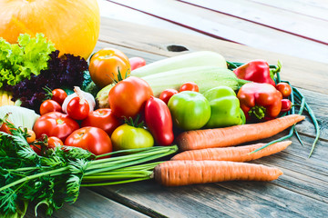 The harvest of vegetables. Vegetables (carrots, corn, cucumbers, tomatoes, onions, garlic, corn, pepper and others) are laid out on a wooden background. Studio photography. Healthy and natural food.