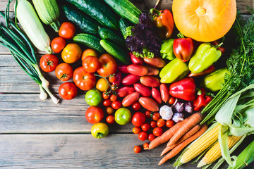 The harvest of vegetables. Vegetables (carrots, corn, cucumbers, tomatoes, onions, garlic, corn, pepper and others) are laid out on a wooden background. Studio photography. Healthy and natural food.	
