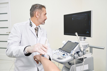 Fototapeta na wymiar Doctor doing ultrasound examination of patinet's wrist.