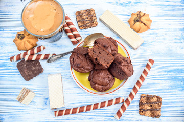 Chocolate muffins and coffee in a glass mug are photographed on a light wooden background.