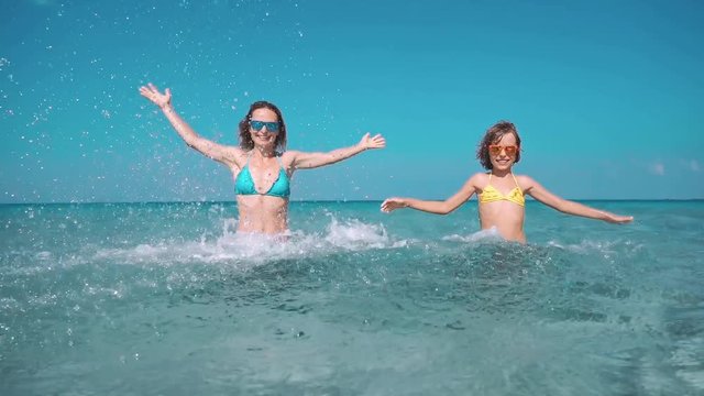 Happy family having fun on summer vacation. Mother and child playing in sea. Active healthy lifestyle concept