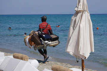 Vendor with counterfeit products on the beach in Chaniotis, Greece. Street vendor selling popular...