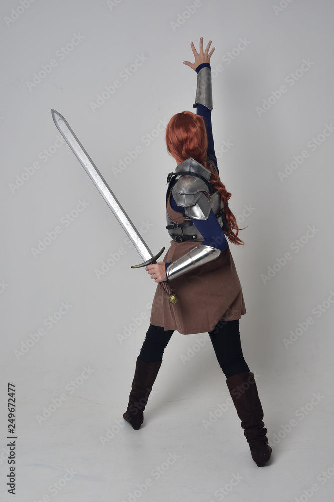 Wall mural full length portrait of a red haired girl wearing medieval warrior costume and steel armour, standin - Wall murals