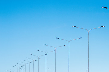 LED road lighting. Road lighting poles. A lot of road lanterns against the blue sky. Metal poles...