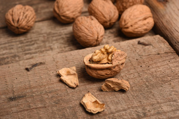 Walnut kernels and whole walnuts on rustic old oak table.
