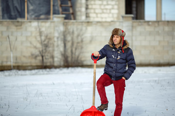 Man with a snow shovel in his hands against background snow