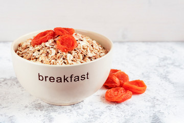 Bowl with cereal flakes and dried apricots on wooden background. The concept of diet, healthy Breakfast.