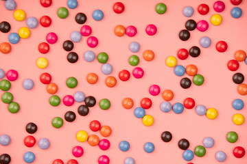 Colorful sprinkles on pink background, flat lay