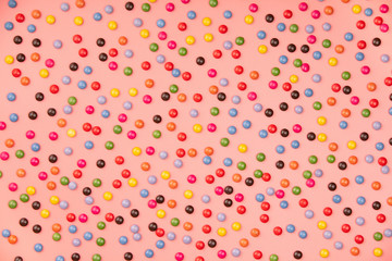 Colorful sprinkles on pink background, flat lay