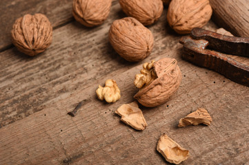 Walnut kernels and whole walnuts on rustic old oak table.