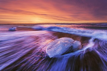 Beautiful sunset over famous Diamond beach, Iceland. This sand lava beach is full of many giant ice gems, places near glacier lagoon Jokulsarlon Ice rock with black sand beach in southeast Iceland